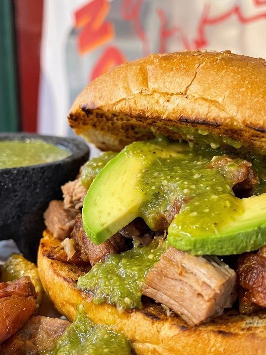 Torta Norteña Sancochi: birote dorado con carnitas, aguacate y salsa verde